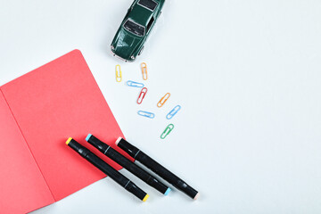 Colorful pencils, clips, red paper and toy car on white background