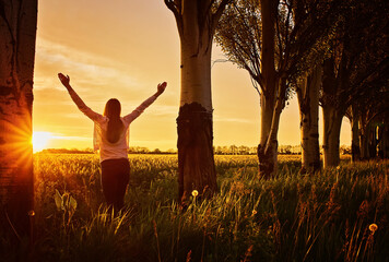 woman feeling victorious facing the beautiful sunset.