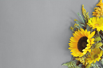 Border of different fresh bright illuminating yellow summer flowers lying on trendy gray background. Flat lay style. Copy space. 2021 color trend - Powered by Adobe