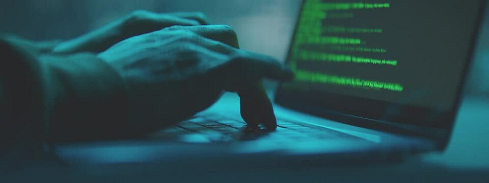 Male hands working on laptop at night in the modern workspace. Male Hands are typing a code on a keyboard.