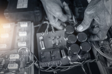 Wrinkled hands of a local electrician man working in his electronic repairs shop.