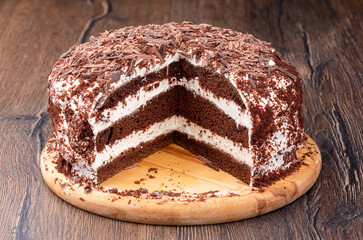 Creamy chocolate cake sprinkled with chocolate chips with a cut.
