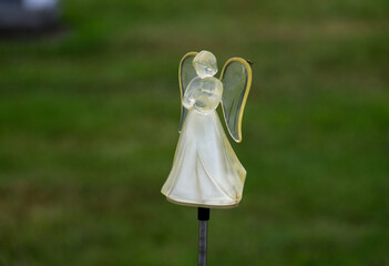 small glass angle grave marker ornament standing in a cemetery alone