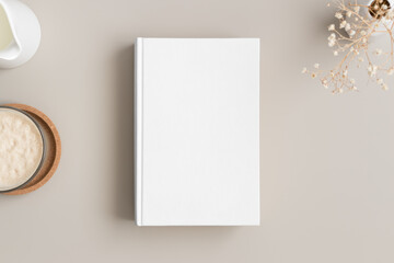 White book mockup with a gypsophila, coffee and a bottle of a milk on the beige table.