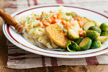 Vegan Schnitzel on noodles with a creamy tarragon vegetable sauce and Brussels sprouts.