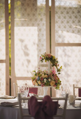 Wedding decoration with pink flowers in vases. The table for guests, served with cutlery, flowers and crockery and covered with a tablecloth. Elegant tablescape.