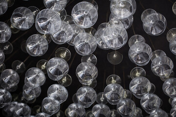 Empty wine glasses hanging up side down on black background.