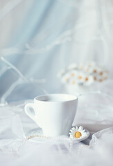 Fototapeta na wymiar Background with white cup and bouquet of white flowers in basket on white background, summer decor