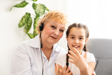 A small girl and grandmother in headphones at home