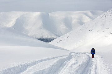 Fototapeta na wymiar The figure of a climber man against the backdrop of a beautiful mountain landscape. Snowy winter.