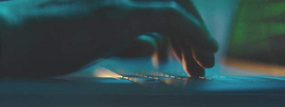 Male hands working on laptop at night in the modern workspace. Male Hands are typing a code on a keyboard.