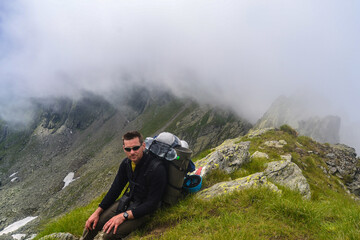 Obraz premium Man hiking at sunset mountains with heavy backpack Travel Lifestyle wanderlust adventure concept summer vacations outdoor alone into the wild