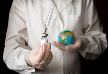 Doctor's hand holding syringe, bottle for vaccine and the globe. Development and creation of a coronavirus vaccine COVID-19. Vaccination against covid-19. Selective focus