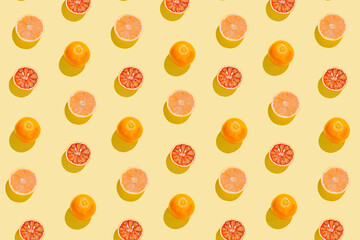 Creative pattern made with sliced grapefruit and blood orange on yellow background. Summer fruit...