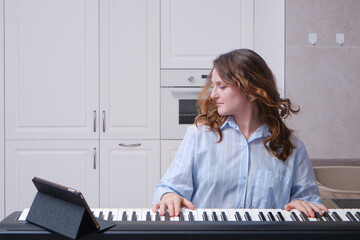 Happy woman playing home digital piano cheerfully and mischievously. Flying hair in time with the shaking of the head