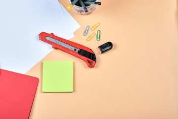 Office supplies, white paper, notebook, pencil and clips on orange background