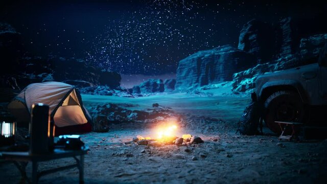 People Camping at Night in the Canyon, Preparing to Sleep in the Tent. Campfire Slowly Burning. Amazing Natural Landscape View with Marvelous Bright Milky Way Stars Shining on Mountains. Zoom in Shot