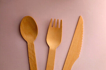Wooden spoons, forks and knives on pastel pink background. Top view.