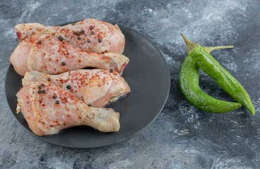 Raw chicken drumsticks with fresh organic peppers
