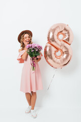 Joyful contented young woman wearing pink dress received bouquet flowers