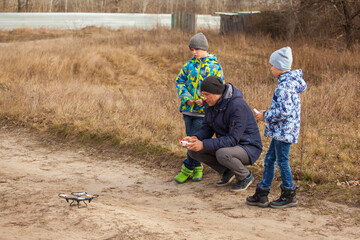 A man with the boys launches a drone against the backdrop of a spring landscape
