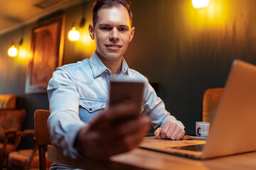 Fototapeta premium Freelance concept. Handsome young man working on laptop computer while sitting at cafe.