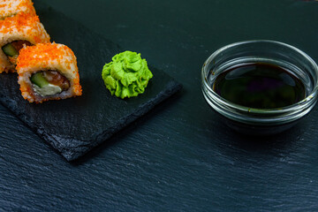 Sushi roll philadelphia with salmon, rice, cheese, cucumber, avocado and caviar on a slate board. Japanese food