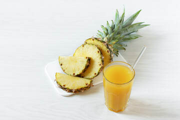 Pineapple fresh juice in glass on white wooden table.