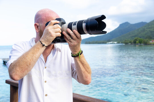 Photographer takes a photo with a DSLR camera near tropical ocean water