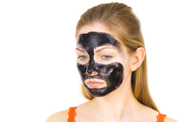 Woman applying black cleanser mask to face
