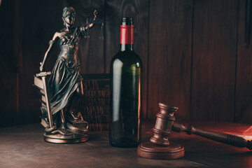Bottle of wine and lady of justice and wooden gavel as a symbol of law. Alcohol and crimes concept.