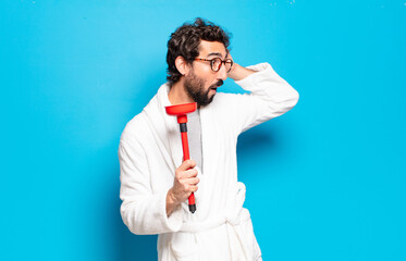 young bearded man wearing bathrobe with a plunger