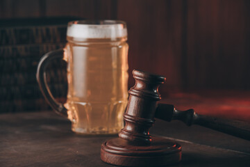 Glass of beer and judge gavel on a wooden table. Alcohol and crimes concept.