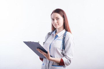 Portrait of a young female doctor in a white uniform with a folder and a pen in hands in the studio on a white background