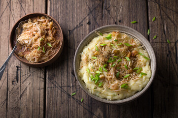 Traditional Irish dish colcannon, mashed potatoes with cabbage and green onions, on top of crispy fried cabbage topping with nuts and spices on a wooden table