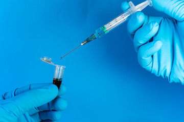 A person mixes, with a syringe, a blood sample with some type of reagent into a microcentrifuge tube. On blue background with copy space.