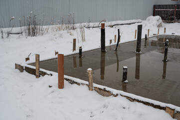 Fresh and wet concrete at house foundation in winter