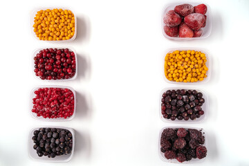 Frozen berries and vegetables in plastic boxes isolated on white background.