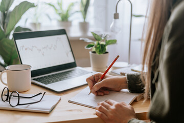 Distance learning online education and work. Business woman with plants writes in notebook. Cropped...
