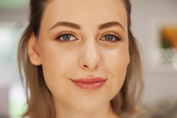 Cute young woman with perfect make-up. Close-up of face of pretty model with natural makeup. Spa and beauty salon, skin care and healthy complexion. Concept of style, satisfaction health. Copy space