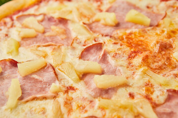 Traditional italian Pizza with ham, mozzarella and pineapple on green grass background