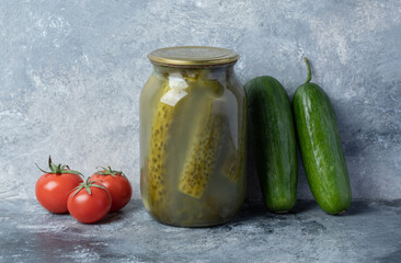 Cucumbers pickled in a glass jar on a marble background