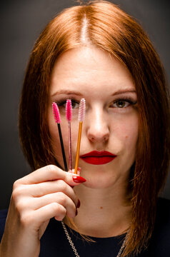 Eyelash extension master holds three multi-colored microbrushes in his hand. eyelash brushes. model on black background