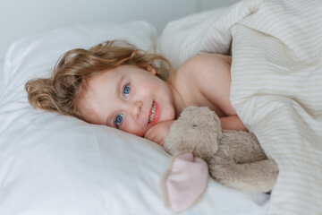 Close-up of a little girl sleeping and hugging her plush rabbit. Relaxation. Healthy sleep.