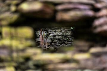 A background of a stone wall, with a hole through which another stone wall can be seen. Bokeh, background