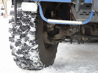 Fototapeta na wymiar Off-road truck big wheel, anti fog lamp, front axle, steering knuckle, brake mechanism, anti-roll bar, front suspension elements and right tire on snow road, 4x4 vehicle construction close up