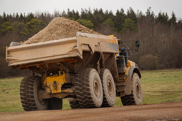 Obraz premium a yellow Volvo A40E articulated earth mover with full 25 tonne payload navigates across Salisbury Plain, Wiltshire UK