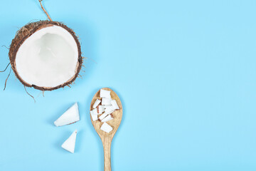 Whole coconut and pieces of coconut on wooden spoon