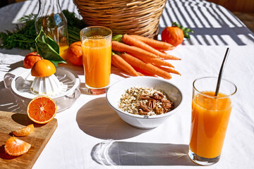 Glass of fresh squeezed orange juice on the table of the kitchen. Ripe bio citrus fuits and vegetables in background.