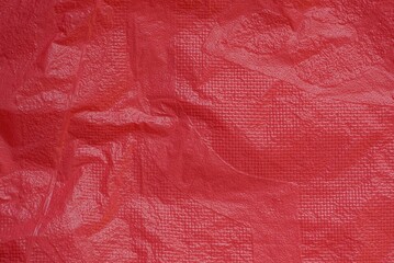Fototapeta premium Plastic background of a piece of crumpled red bright cellophane